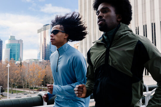Fit men exercising side by side, framed by sleek office towers
