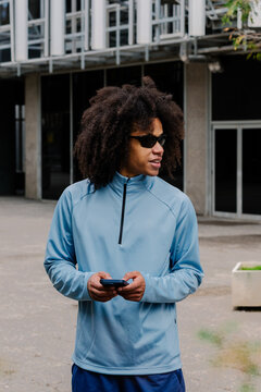 Smiling young athlete holding his smartphone to track fitness data