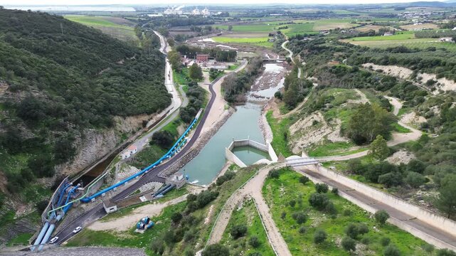 A cinematic 4K aerial drone video filmed over the water discharge and spillway infrastructure of Embalse de Guadalcacin in Cadiz Andalusia Spain. The drone flies above the outflow channel pipes and