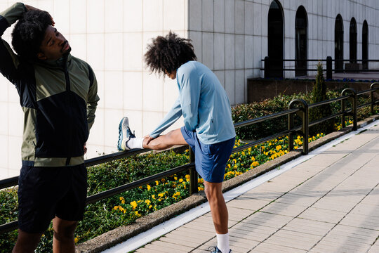Two athletic men stretching before starting a morning cardio workout