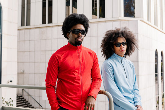 Fit men posing confidently side by side, set against office towers