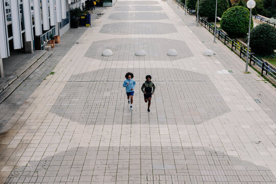 Elevated wide perspective showing two male athletes running on a city