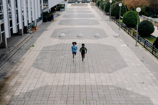 Men running in a pedestrian corridor bordered by office buildings