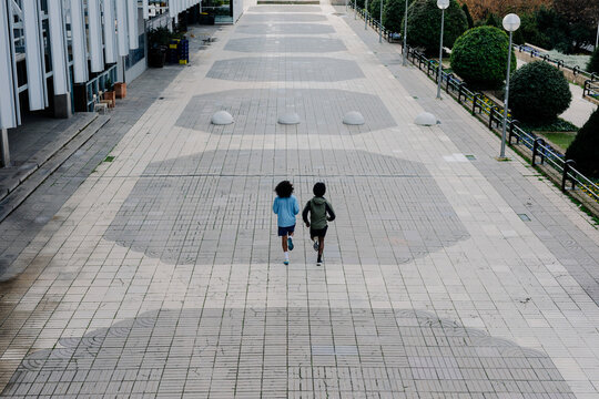Two men jogging along a walkway flanked by contemporary office towers