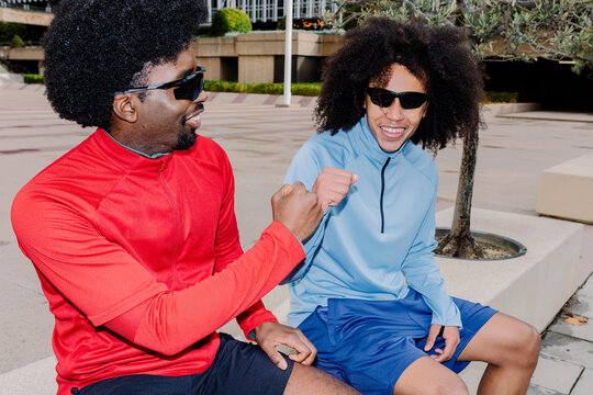 Portrait lit with flash of two athletes bumping fists on a bench