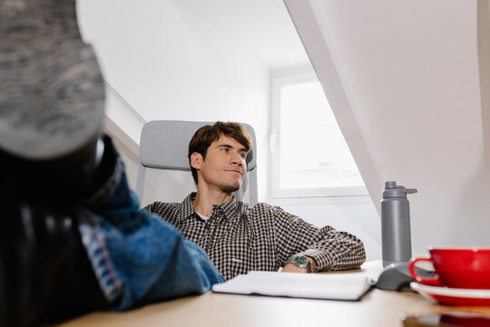 Entrepreneur enjoying a break, with his feet propped up on his desk