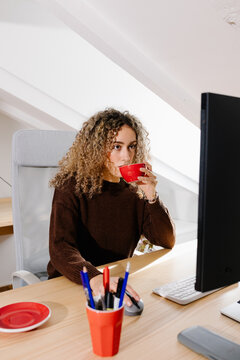 Woman at a home workspace, engaged in a video conference