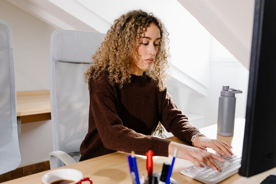 A freelance woman at a home desk, focused on her computer