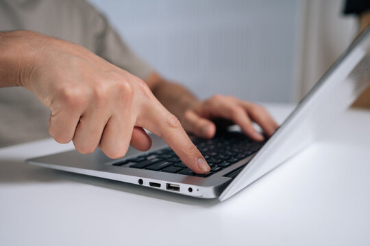 Person finger pressing laptop power button, turning on or off portable computer, starting modern technology or shutting down electronic device at home office for work or study, close-up, cropped shot