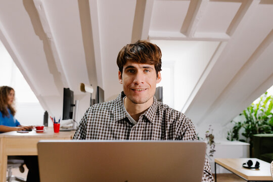 Mid-range portrait of a freelance man seated at his home office desk