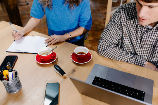 Messy desk with a couple of freelancers working together with a laptop