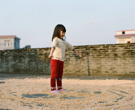 Asian girl drying corn on rooftop balcony