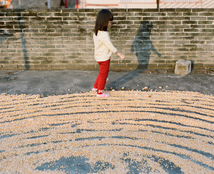 Asian girl drying corn on rooftop balcony