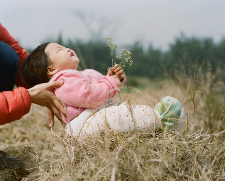 Closeup of cute asian child laughing heartily while lying on haystack 