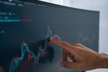 Trader hand pointing at live financial chart on computer monitor, analyzing price movements and data visualization for crypto investments and stock market speculation, close-up, cropped shot © dikushin