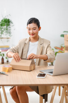 Asian woman preparing a package for shipping from her home