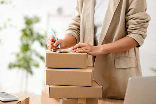 Woman writing on a notepad while preparing packages for shipment