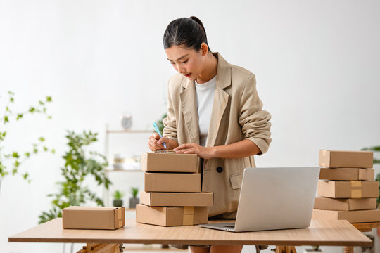 Asian woman preparing packages for shipment in her home office