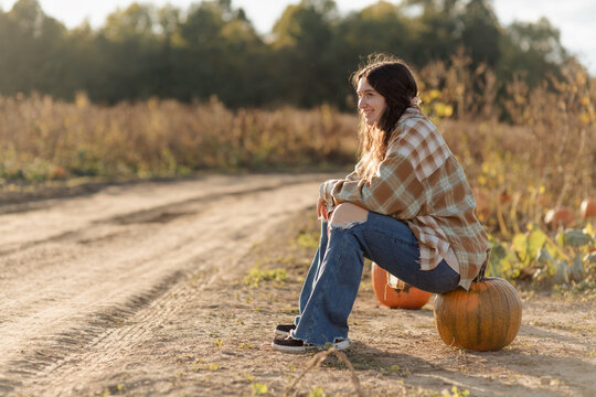 A young woman picking a pumpkin at a pumpkin patch in October.