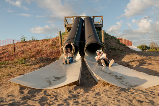 A brother and sister going down a slide at a pumpkin patch in October.
