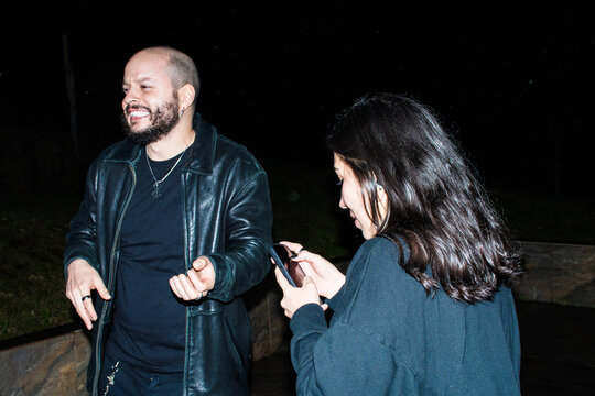 Friends dancing and Using Phones at Night Outdoors