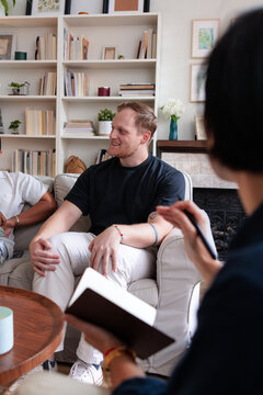Couple in therapy session with therapist taking notes.