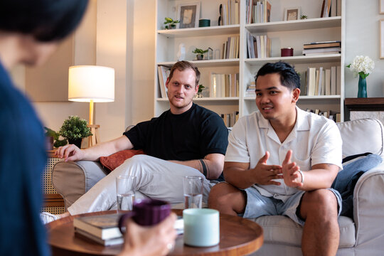 Two men converse with a person holding a mug.