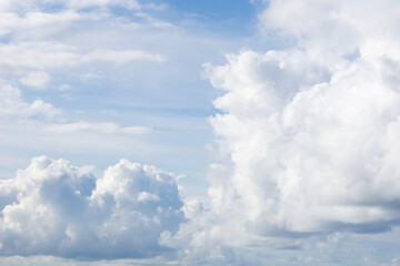 Obraz premium a wide angle shot of a large fluffy white cumulus cloud against a bright blue sky with soft light and copy space