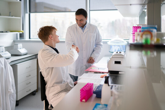 Senior and Junior Scientists Shaking Hands in Lab