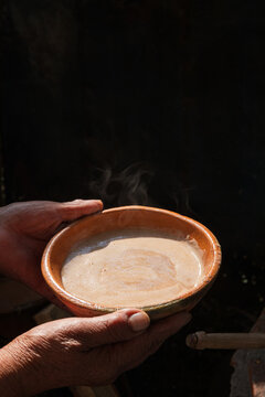 Bowl of steaming traditional cacao drink in hands