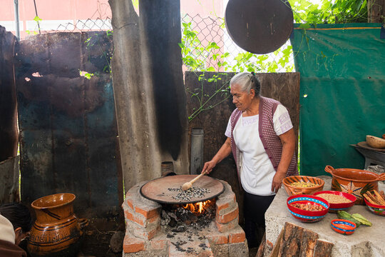 Woman toasting corn in a rustic kitchen in Mexico