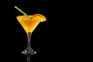 Refreshing orange cocktail in martini glass on black