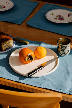 Close-up of a plate with an orange and a persimmon