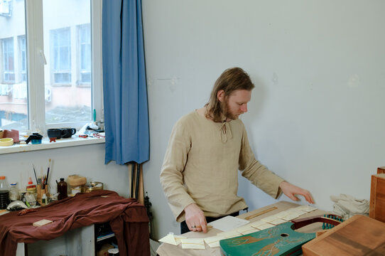 A male musical instrument maker selects strings for an instrument 