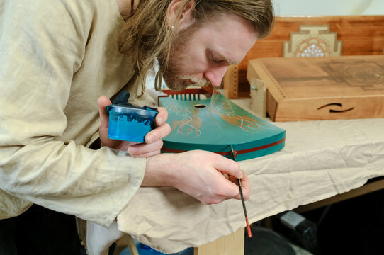 A musical instrument maker repaints an instrument