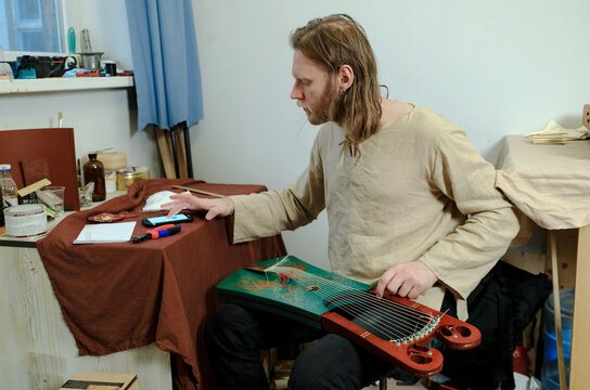 A luthier attaches strings to an instrument.