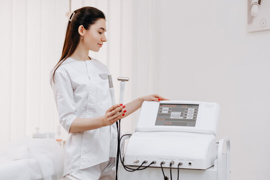 Esthetician operating professional facial device in modern clinic performing skin treatment with advanced beauty equipment