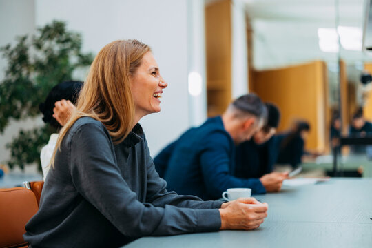 Smiling Woman At Office Table During Meeting