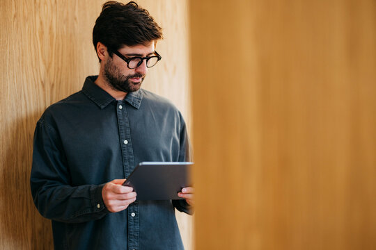 Man With Tablet Reading In Wooden Hallway