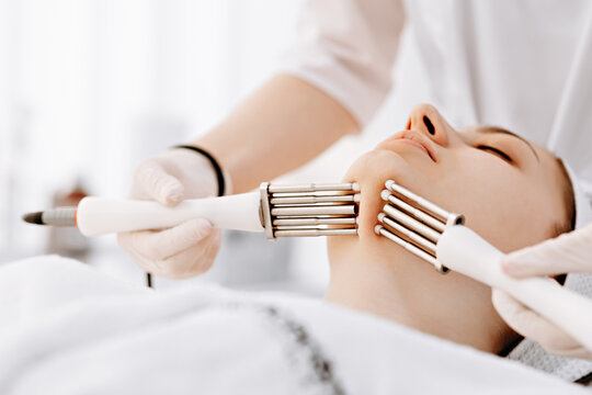 Woman receiving professional microcurrent facial treatment for skin tightening and anti-aging in spa clinic