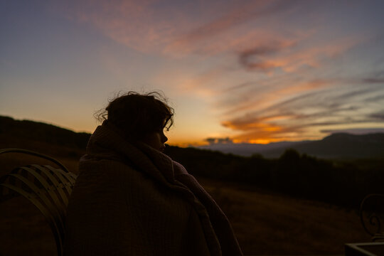 Child silhouette sitting quietly at sunset