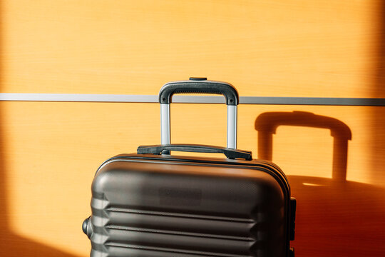 A travel suitcase stands against a wall in an airport.