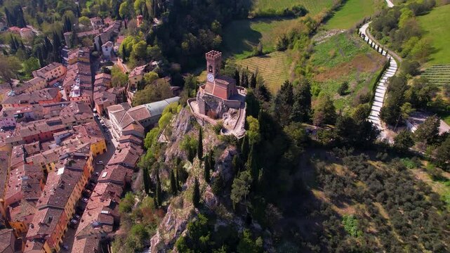Brisighella aerial 4k soft view of clock tower and cypress road in Italy. Scenic hilltop village in Emilia Romagna with traditional red roofs and Torre dell Orologio. Authentic travel scenery