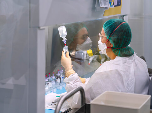 Pharmacist compounding medicine in hospital pharmacy sterile hood