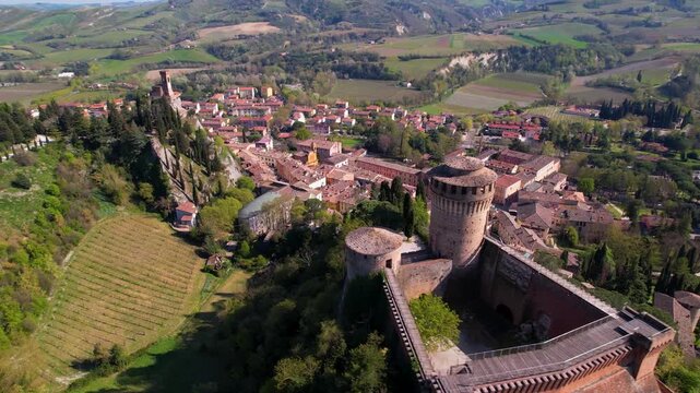 Brisighella aerial 4k flight from medieval castle to clock tower in Italy. Scenic drone reveal of Rocca Manfrediana and Torre dell Orologio on cliffs. Emilia Romagna hilltop village scenery