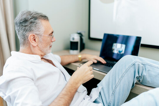 Senior man relaxing in hotel room using laptop