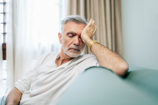 Senior man feeling exhausted and resting in hotel room