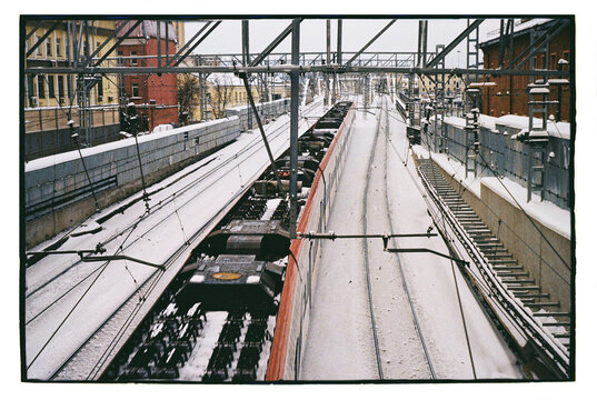 Snow covers train tracks as trains pass through city station