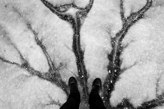 Feet standing on cracked ice on dark winter day