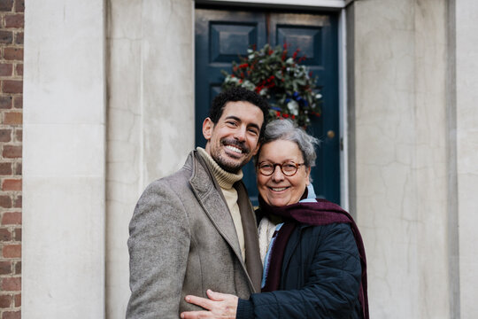 Happy son hugging senior mother celebrating winter holidays